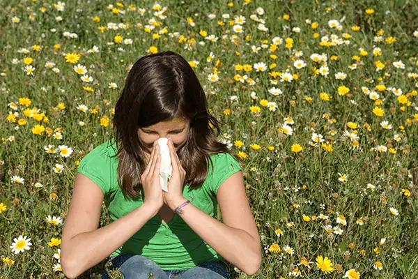 lady allergic to allergens sneexing in meadow with flowers