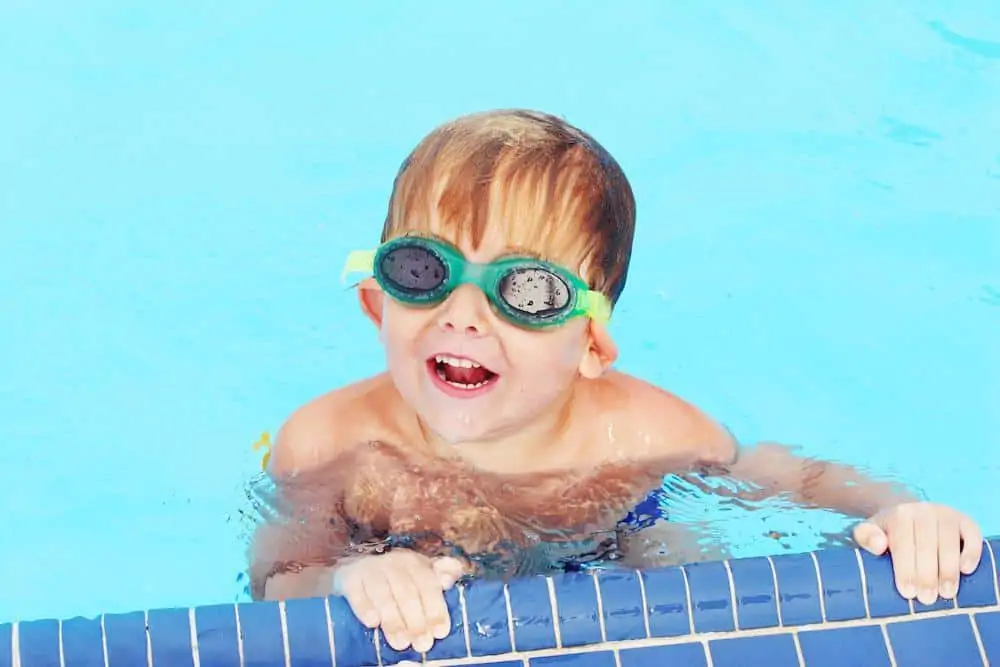 Child swimming int he pool smiling
